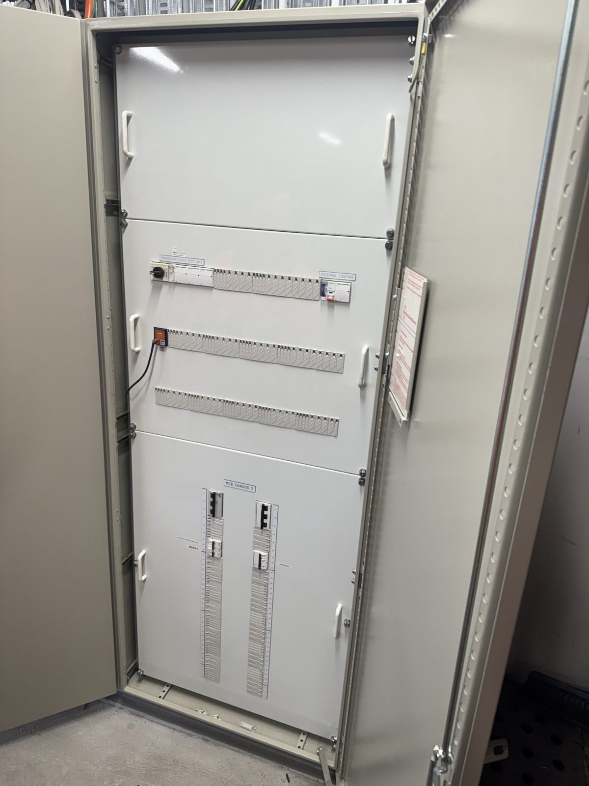 Open distribution board with three MCB chassis, emergency light test unit and sub-main isolators