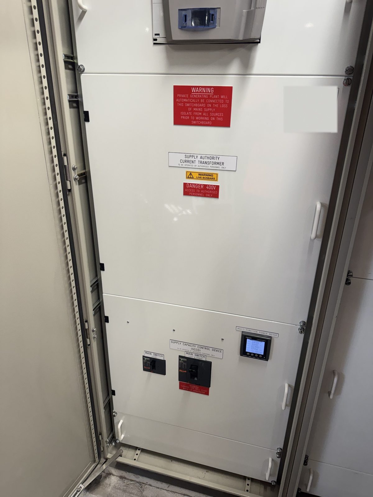 Main switch section of a commercial switchboard with supply capacity control device, multifunction power meter and warning labels